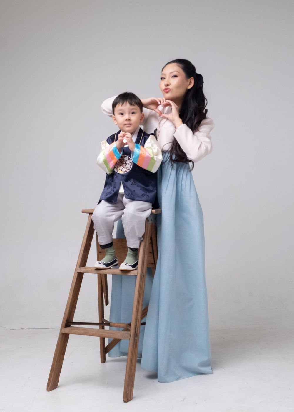 Sequence of four photos showing someone in a light blue dress with a child in gray outfit sitting on wooden step stool.