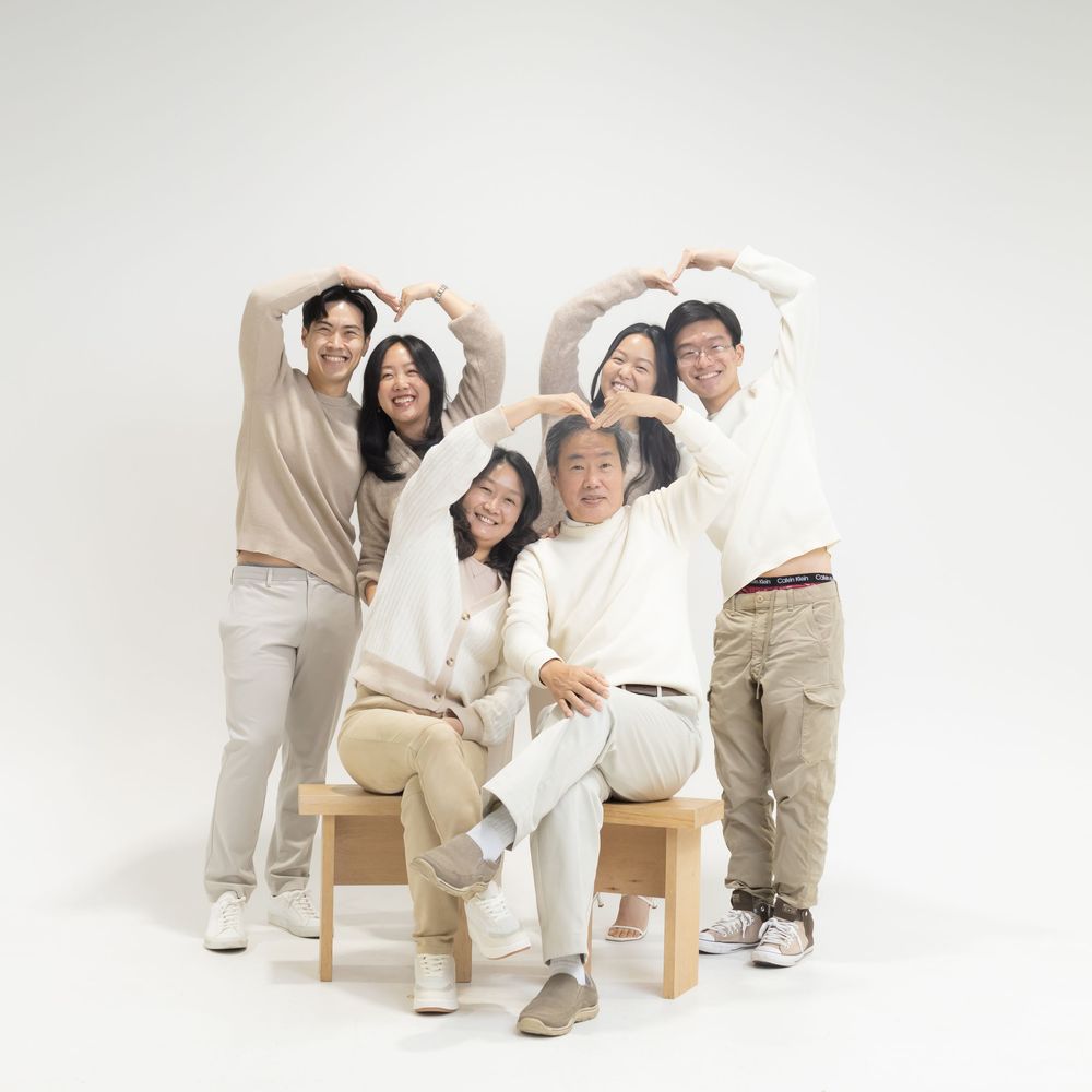 Five people in matching cream and beige outfits posing together playfully against a white studio background.