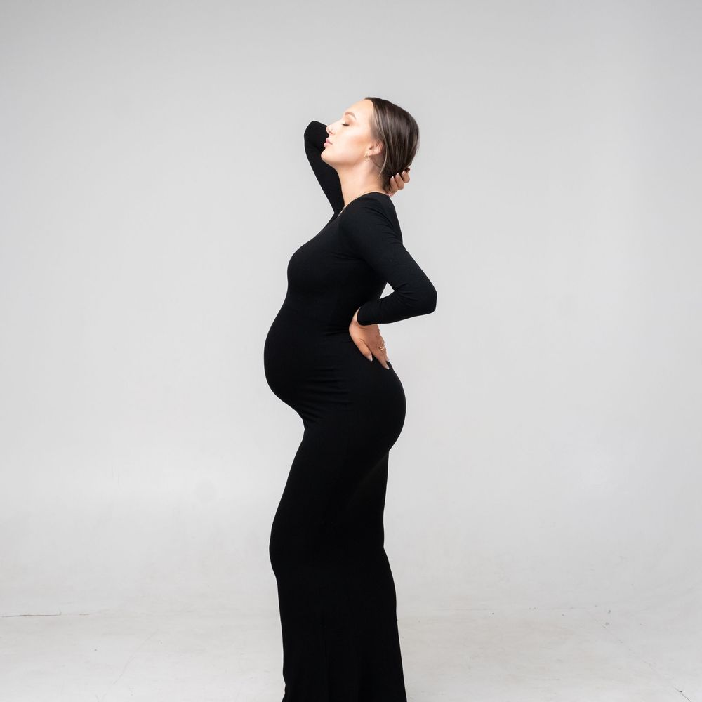 Side profile silhouette of a pregnant woman in black against grey background shown in four artistic poses.