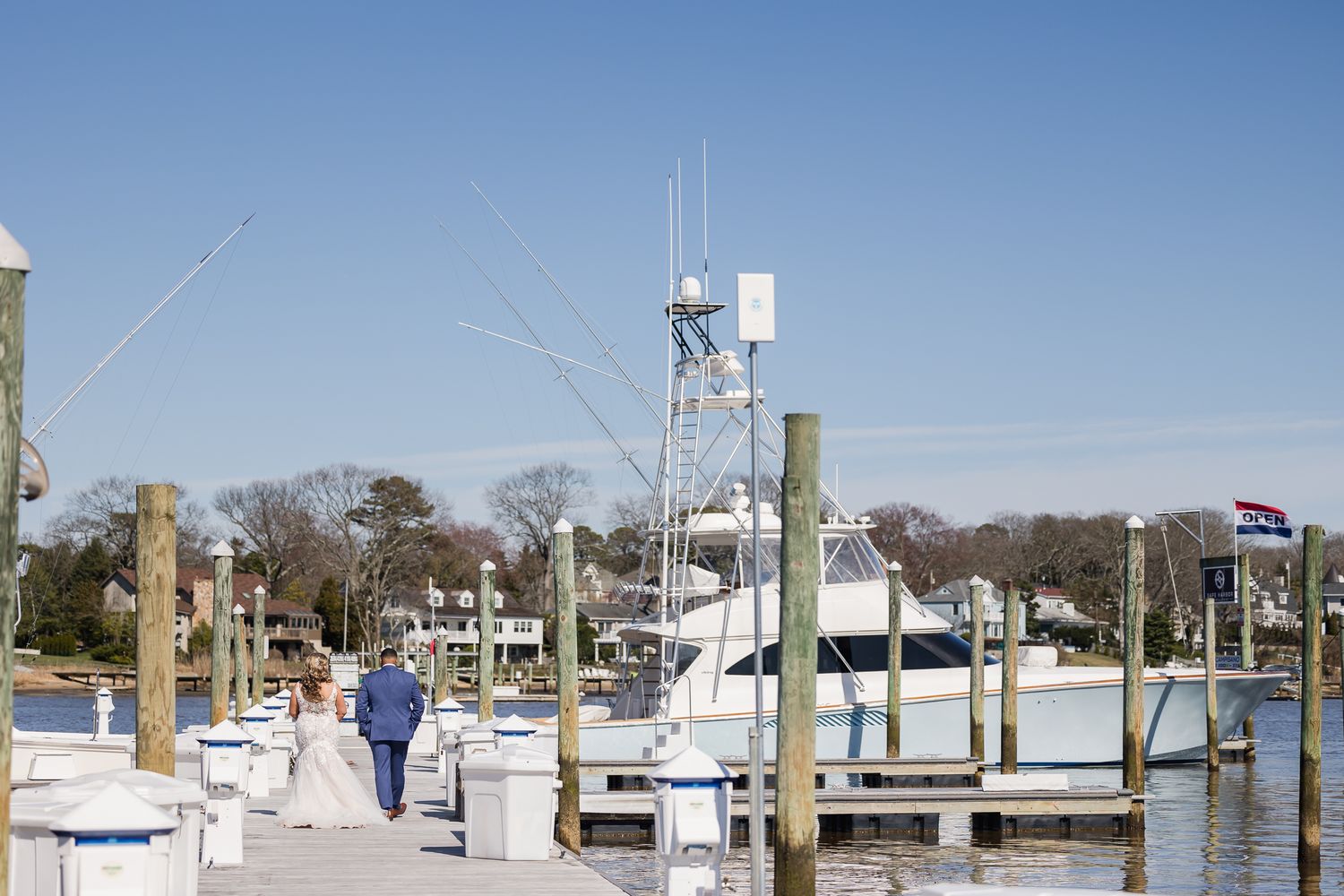 Marina with boats docked at wooden piers under clear blue skies.