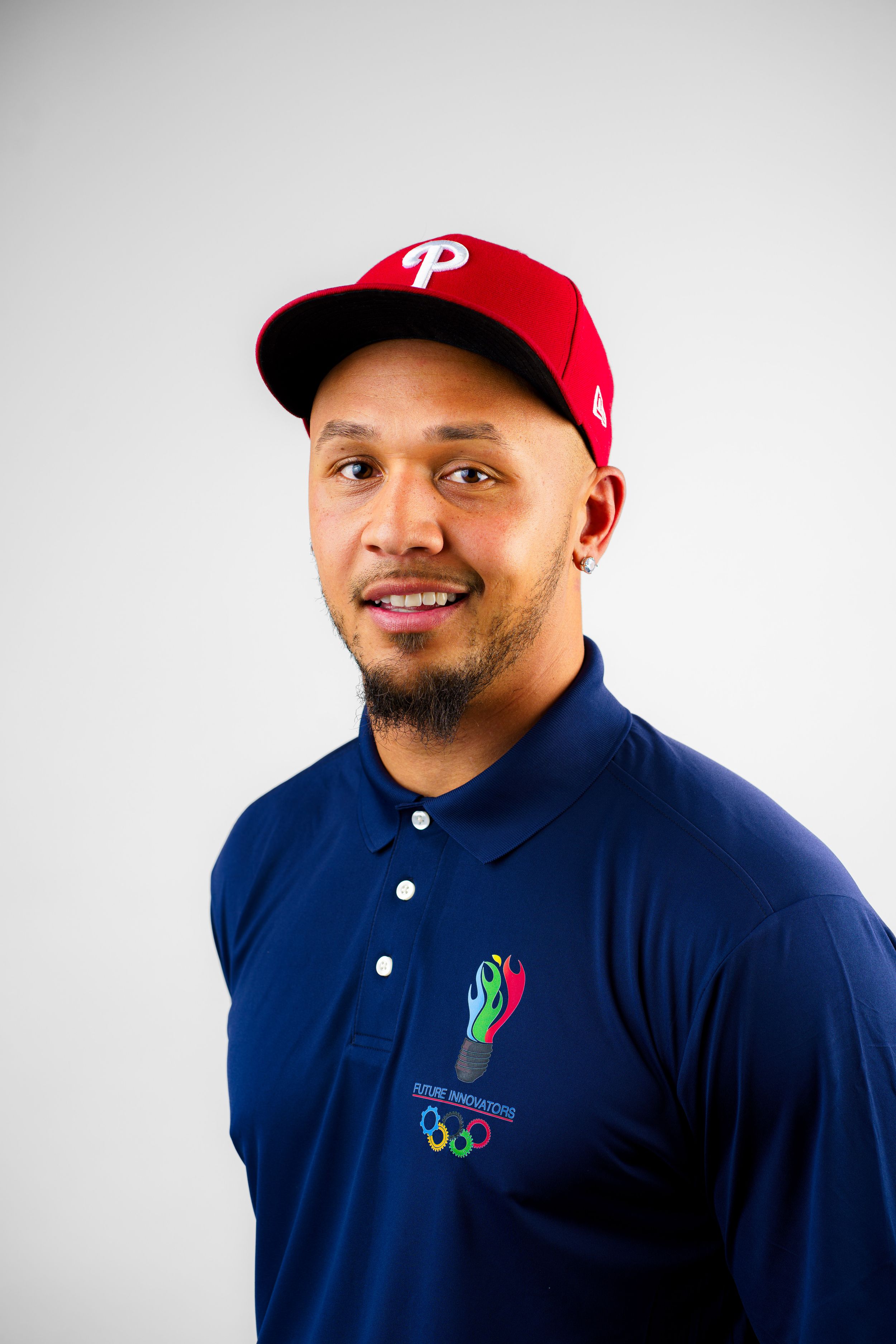 A person wearing a Philadelphia Phillies baseball cap and navy blue polo with an embroidered logo smiles at the camera.