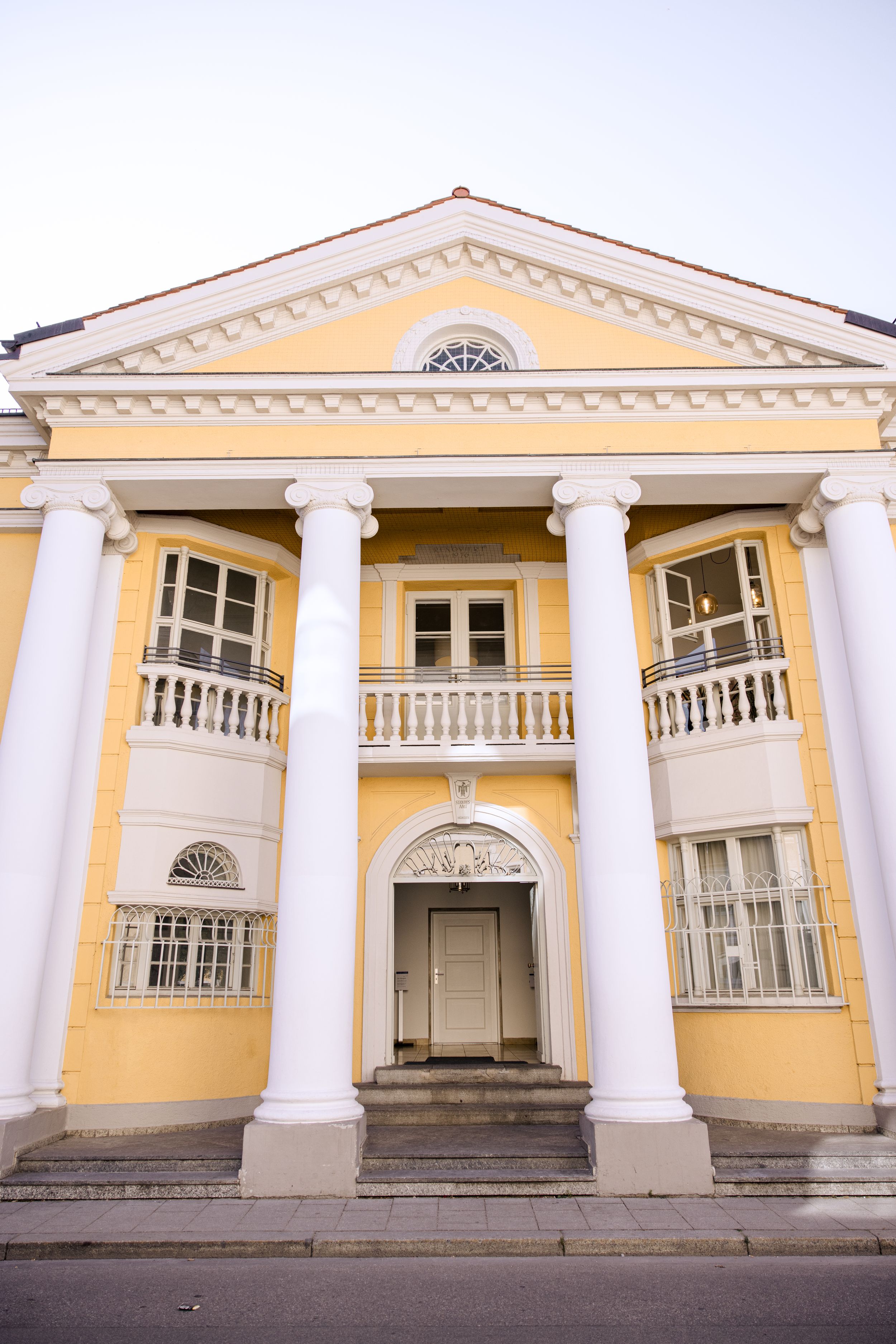 Classical yellow building with white columns and ornate architectural details.