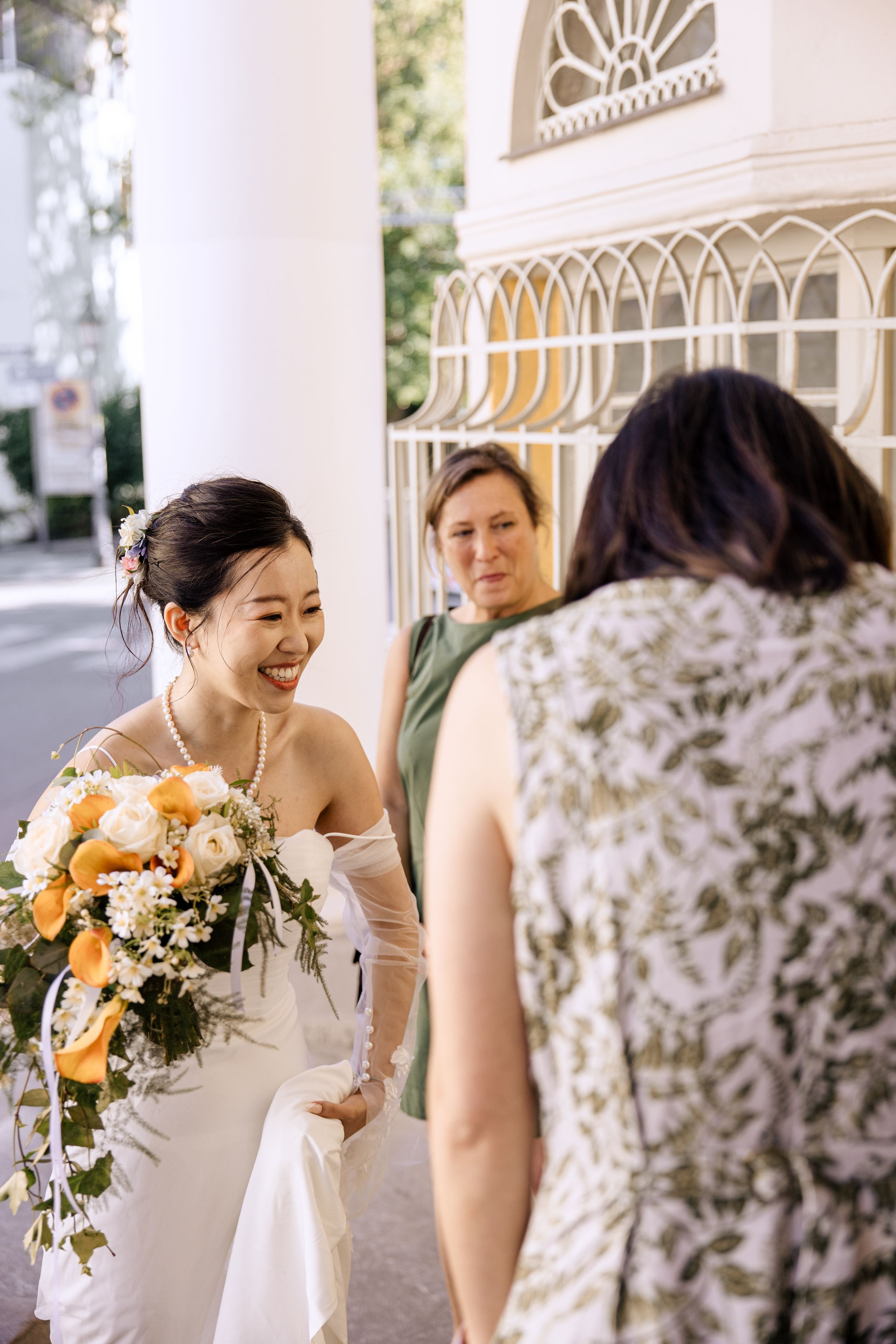 Candid sequence of a bride in white smiling and laughing with her bouquet of orange flowers.