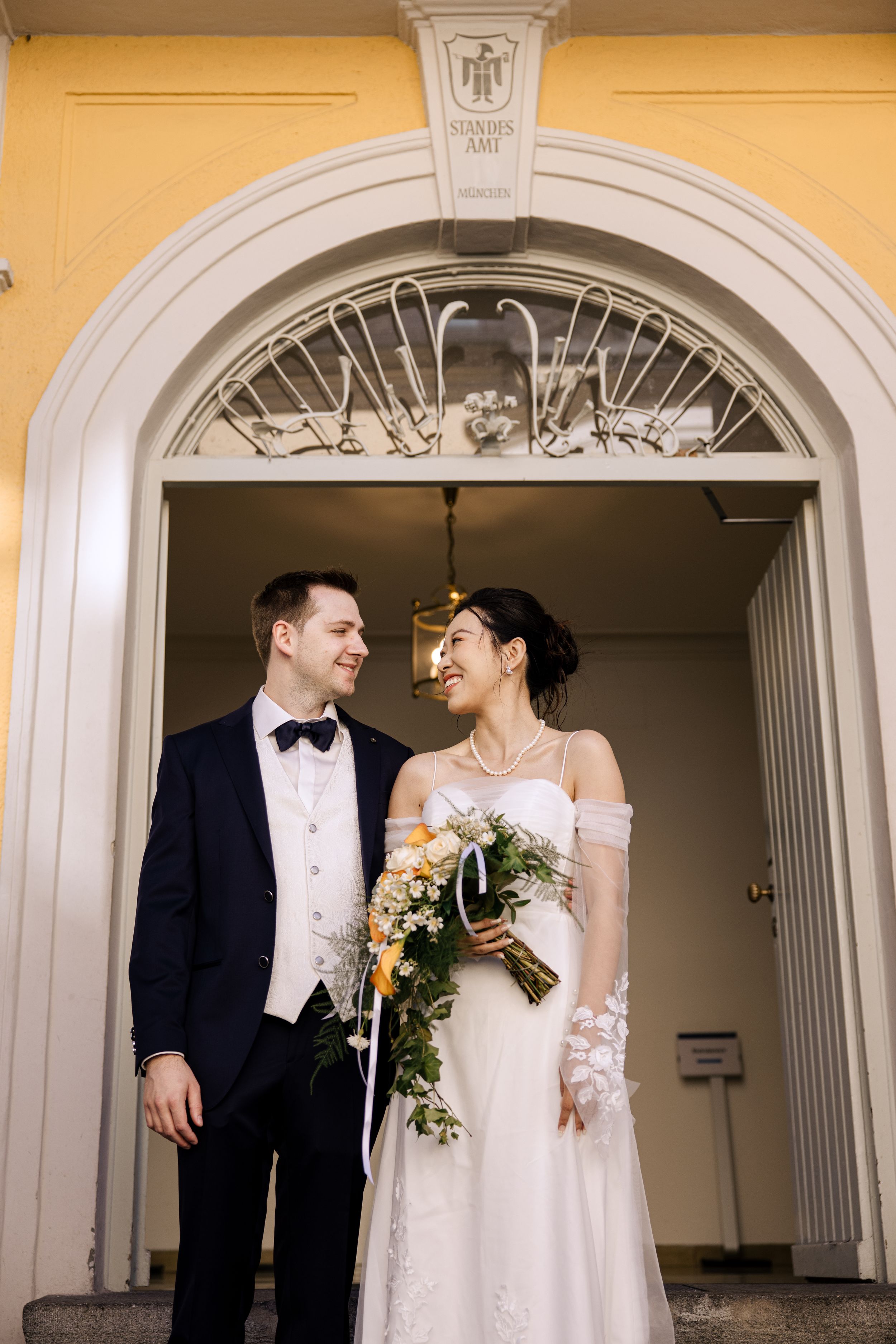 Wedding couple sharing intimate moments under elegant archways with yellow walls.