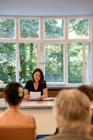 Interior classroom scene with rows of desks and large windows letting in natural light.