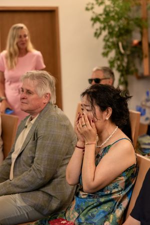 Wedding guests show emotional reactions during ceremony while seated in formal attire.