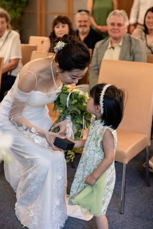 Young flower girl in white dress interacting with wedding party during celebration.