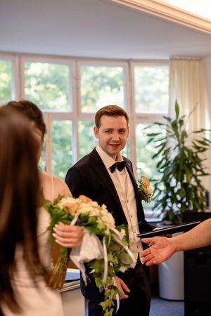 Wedding celebration in bright room with large windows and indoor plants.