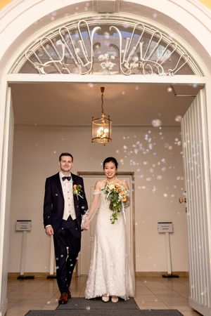 Wedding couple photographed in sequence walking through an elegant archway with white decor.