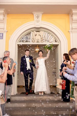 Wedding party celebration with bubbles outside a historic building with arched entrances.