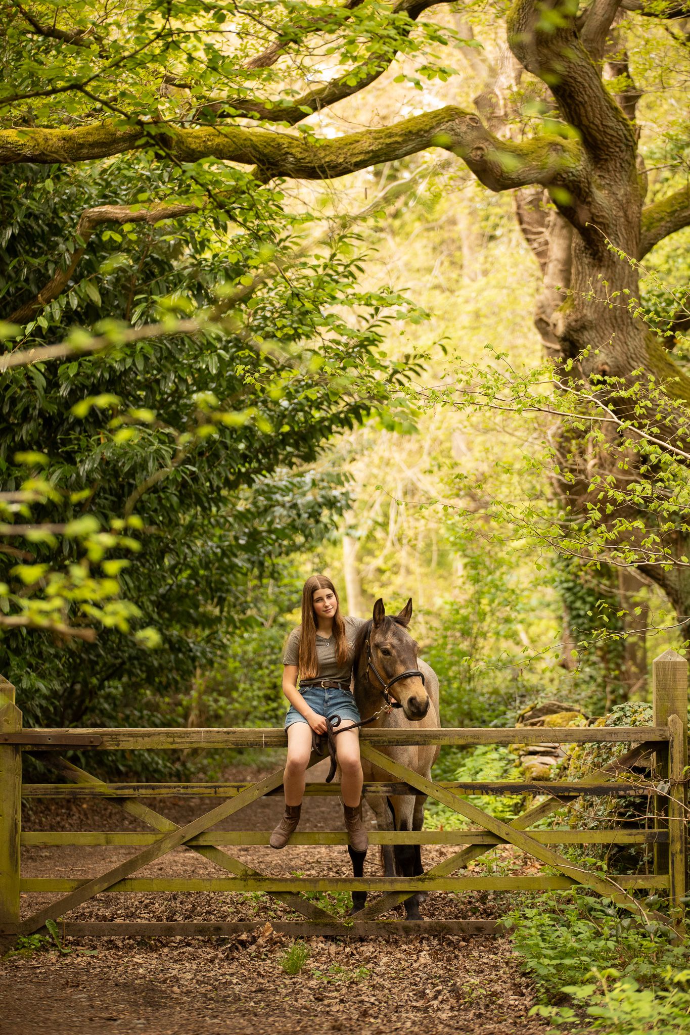 Two Cocker Spaniels sit with their owners on a lawn surrounded by bright yellow spring blooms in the background.