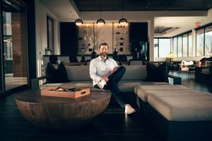 Man sitting relaxed in modern upscale lounge area with coffee table.