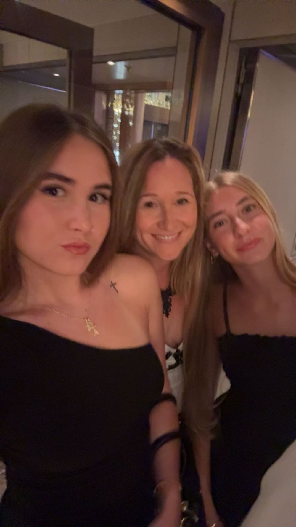 Three friends pose together for a selfie at night while wearing black tops.