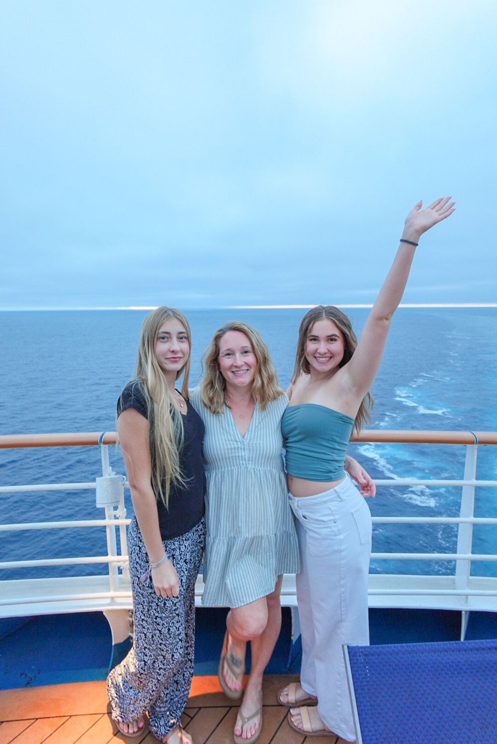 People enjoying a sunny day on a cruise ship deck with blue ocean waters in the background.