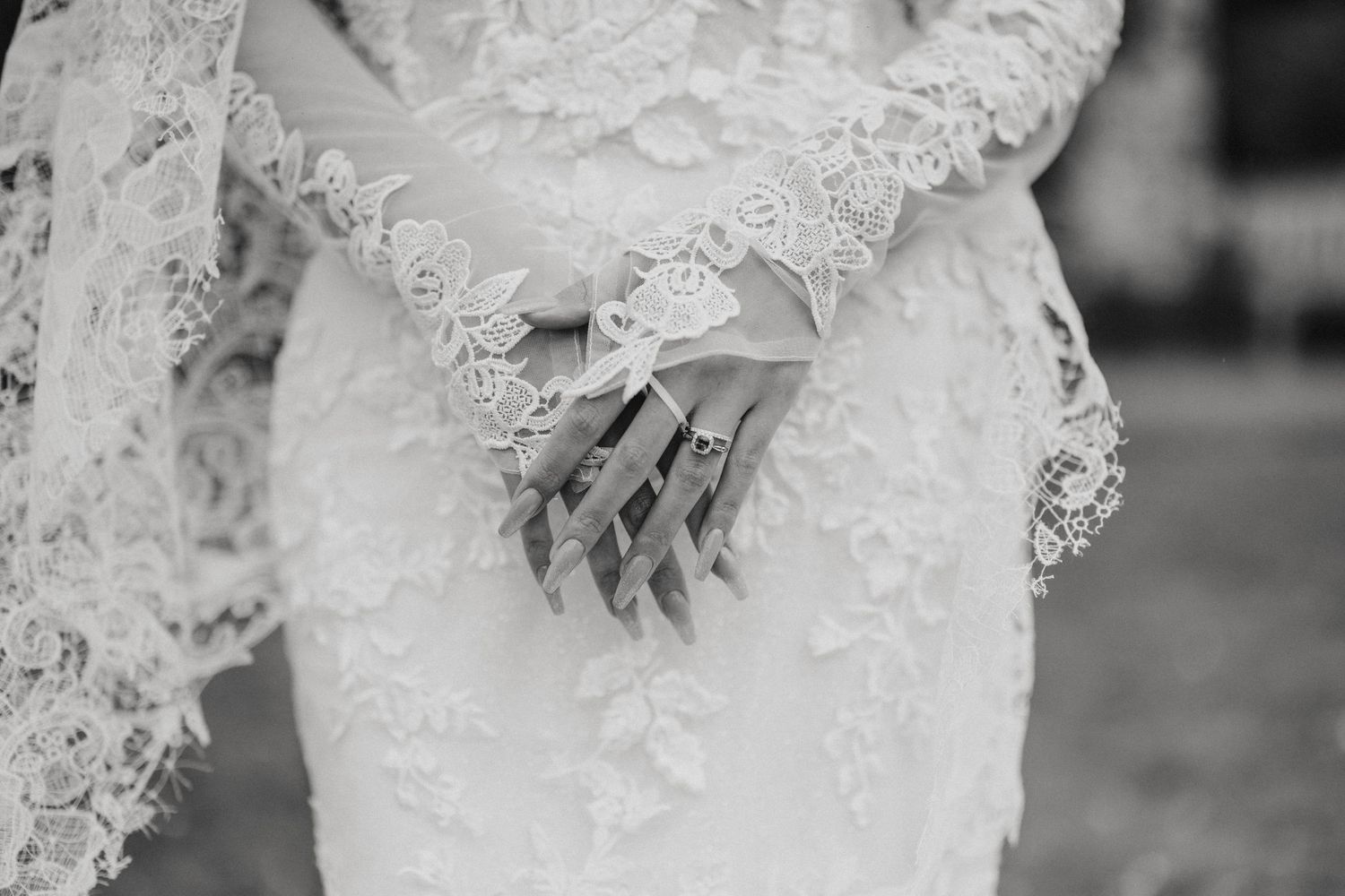 A bride in an elegant white lace gown holds her bouquet during a wedding photoshoot outdoors.