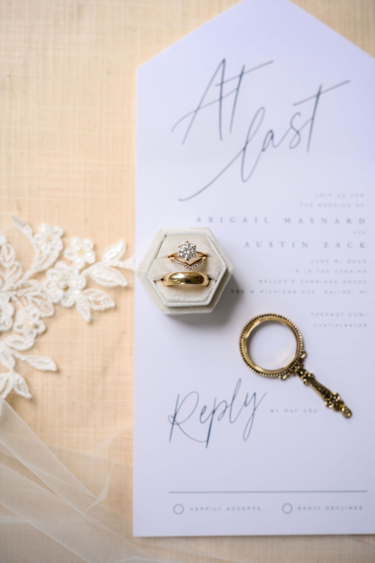 Wedding invitation with a decorative hexagonal ring box and antique key on white paper with elegant calligraphy.