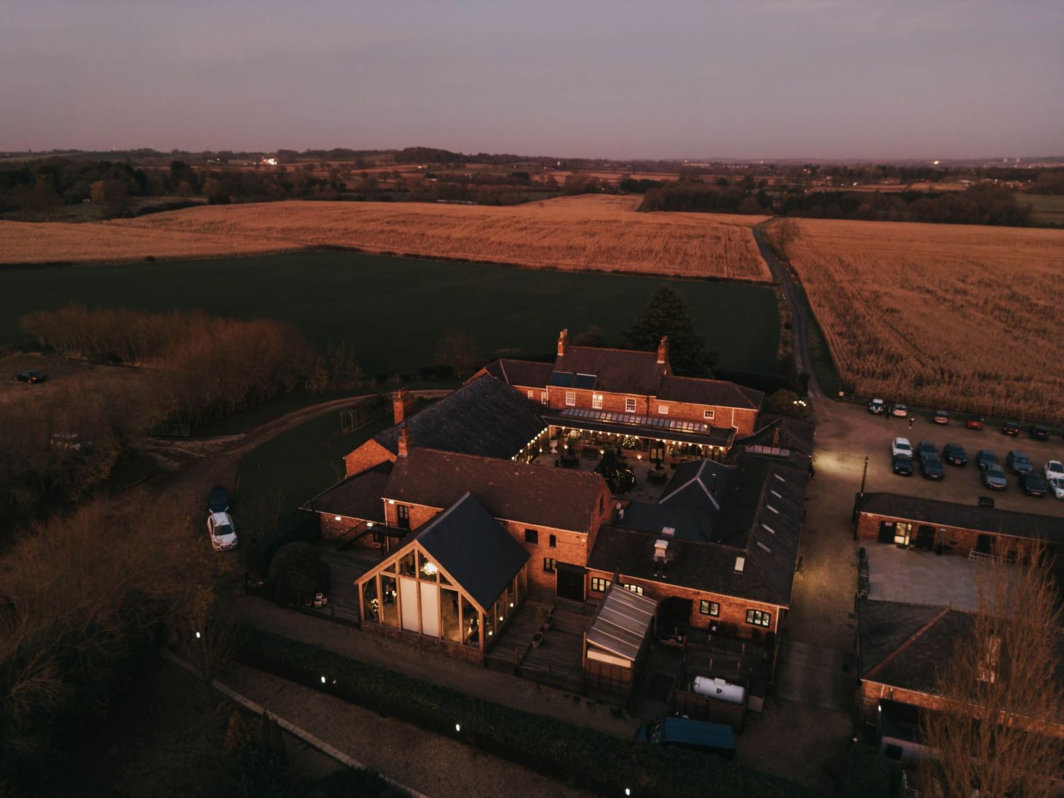 Golden sunset illuminates a rural farm property with aerial views of multiple buildings scattered across rolling hills.