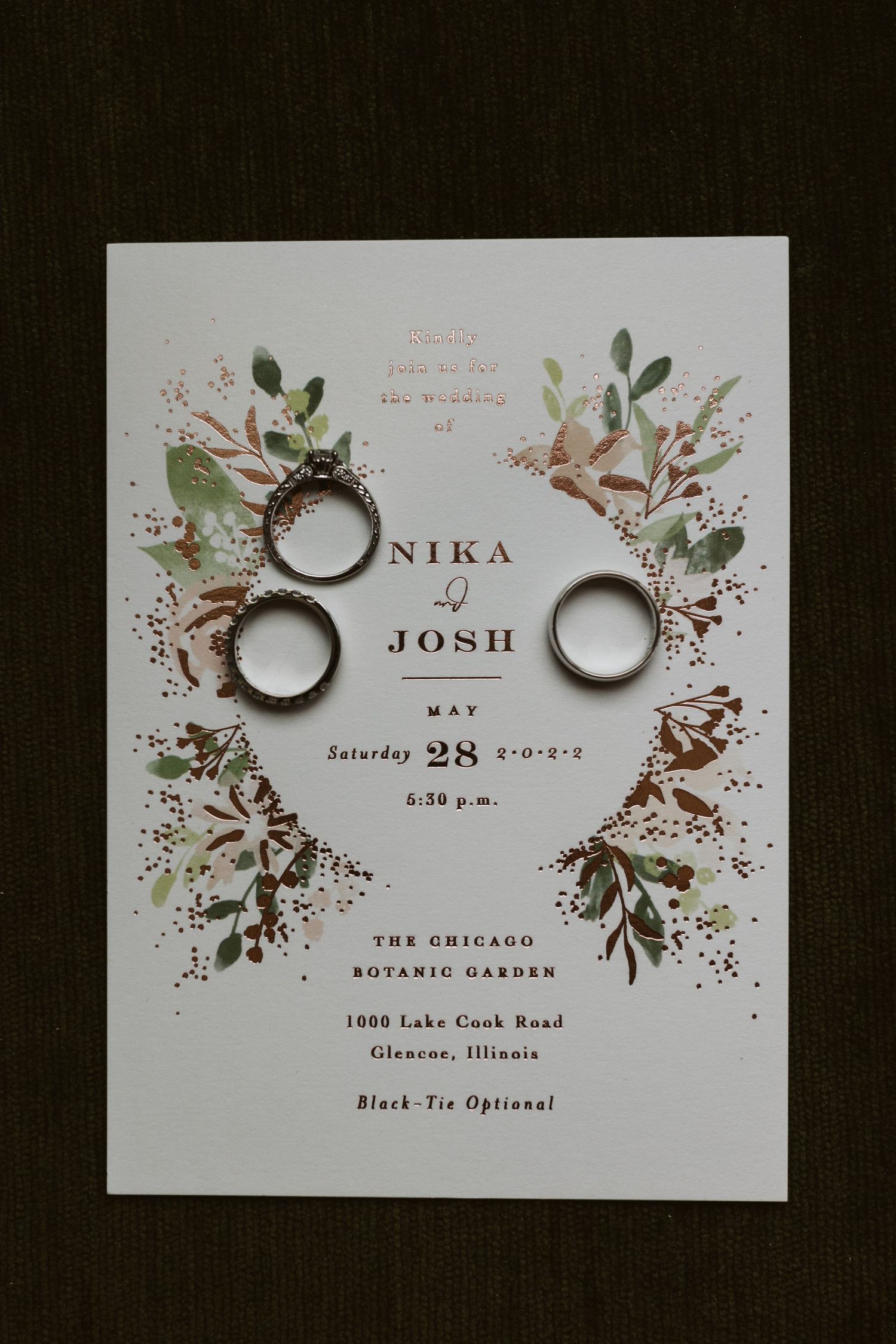 Elegant wedding invitation with floral designs and wedding rings artistically arranged.
