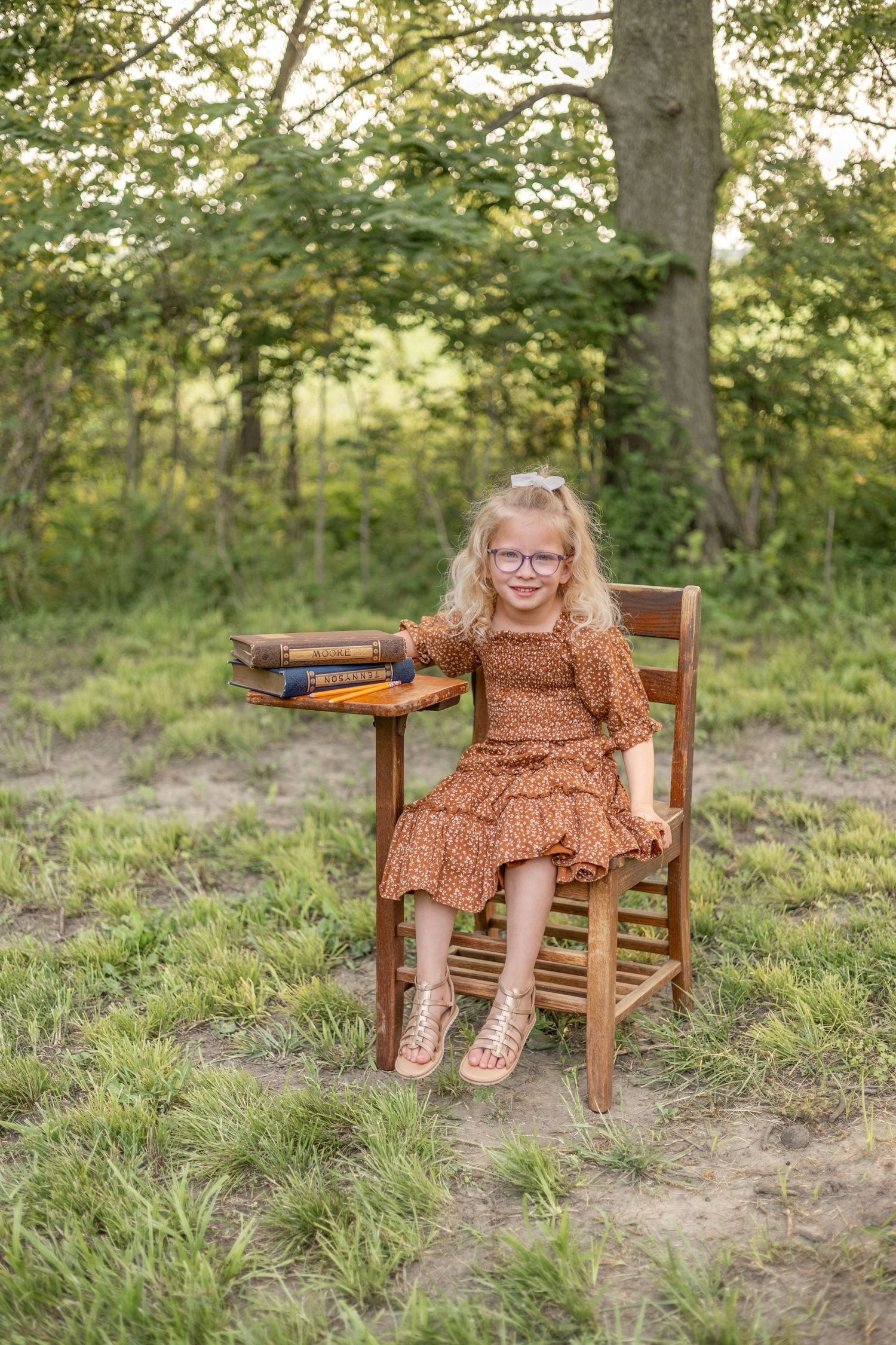 Springfield, IL Photographer captures a girl sitting at an antique wooden desk with a book opened up during a mini session in Central, IL