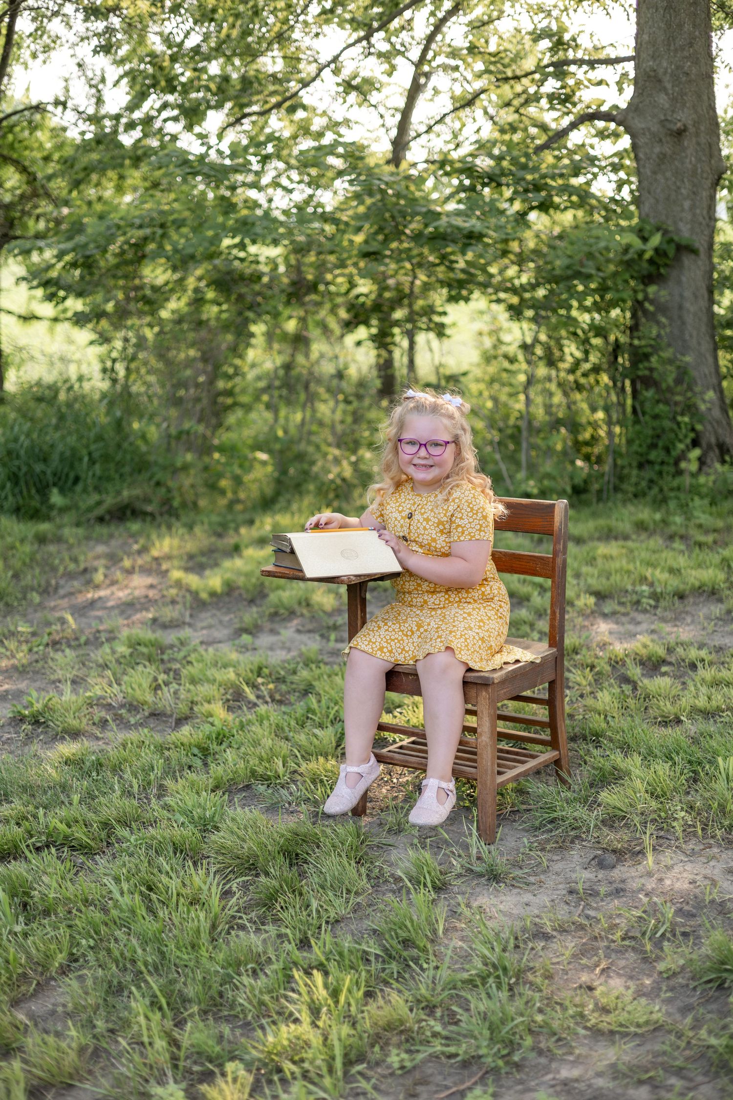 Springfield, IL Photographer captures a girl sitting at an antique wooden desk with a book opened up during a mini session in Central, IL