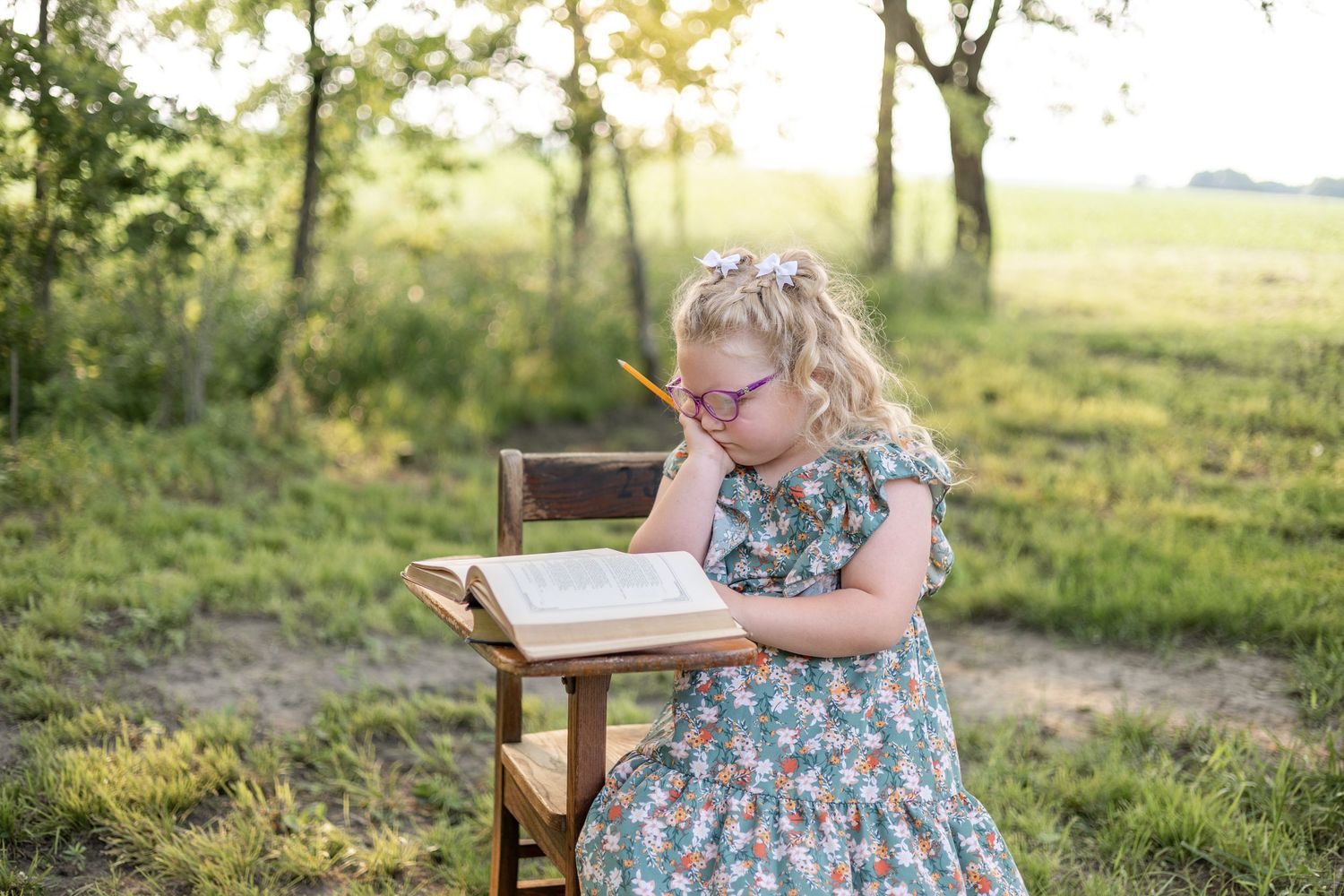 Springfield, IL Photographer captures a girl sitting at an antique wooden desk with a book opened up during a mini session in Central, IL
