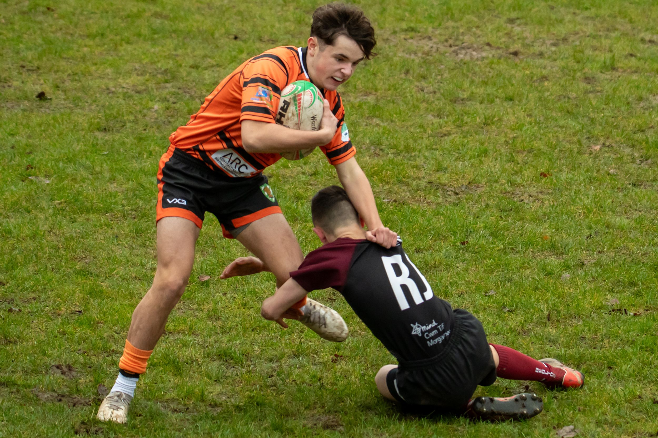 2 Rugby Players involve themselves into a tackle.