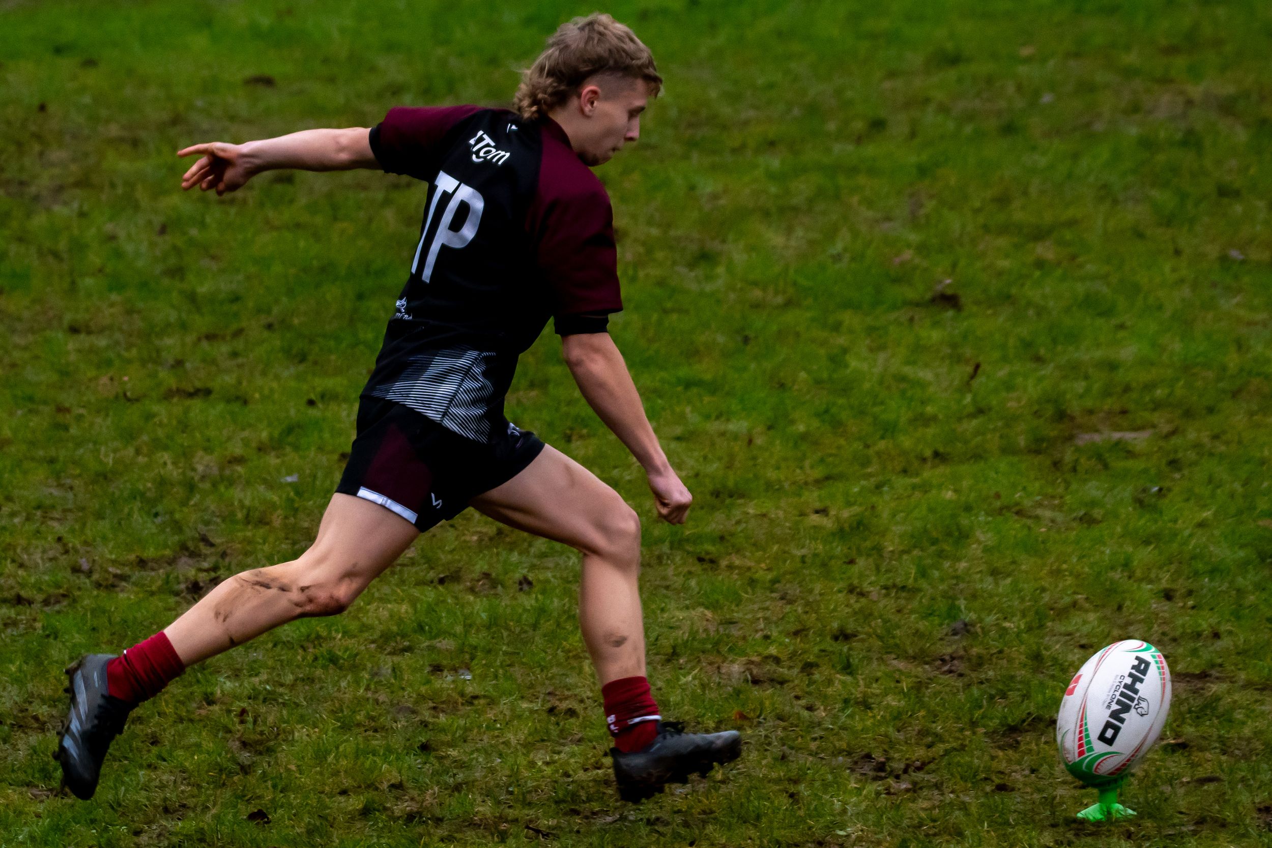 Rugby Player starts running to kick the ball, hoping to get points from the conversion.