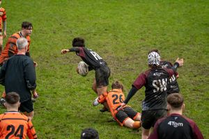 Rugby Player lunges into a tackle, winning their team some time.