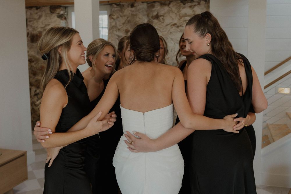 Bridesmaids in black dresses sharing emotional moments during a wedding celebration.