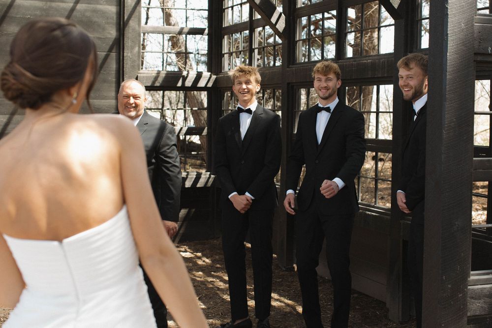 Wedding ceremony setup with attendees in formal attire inside a rustic venue.