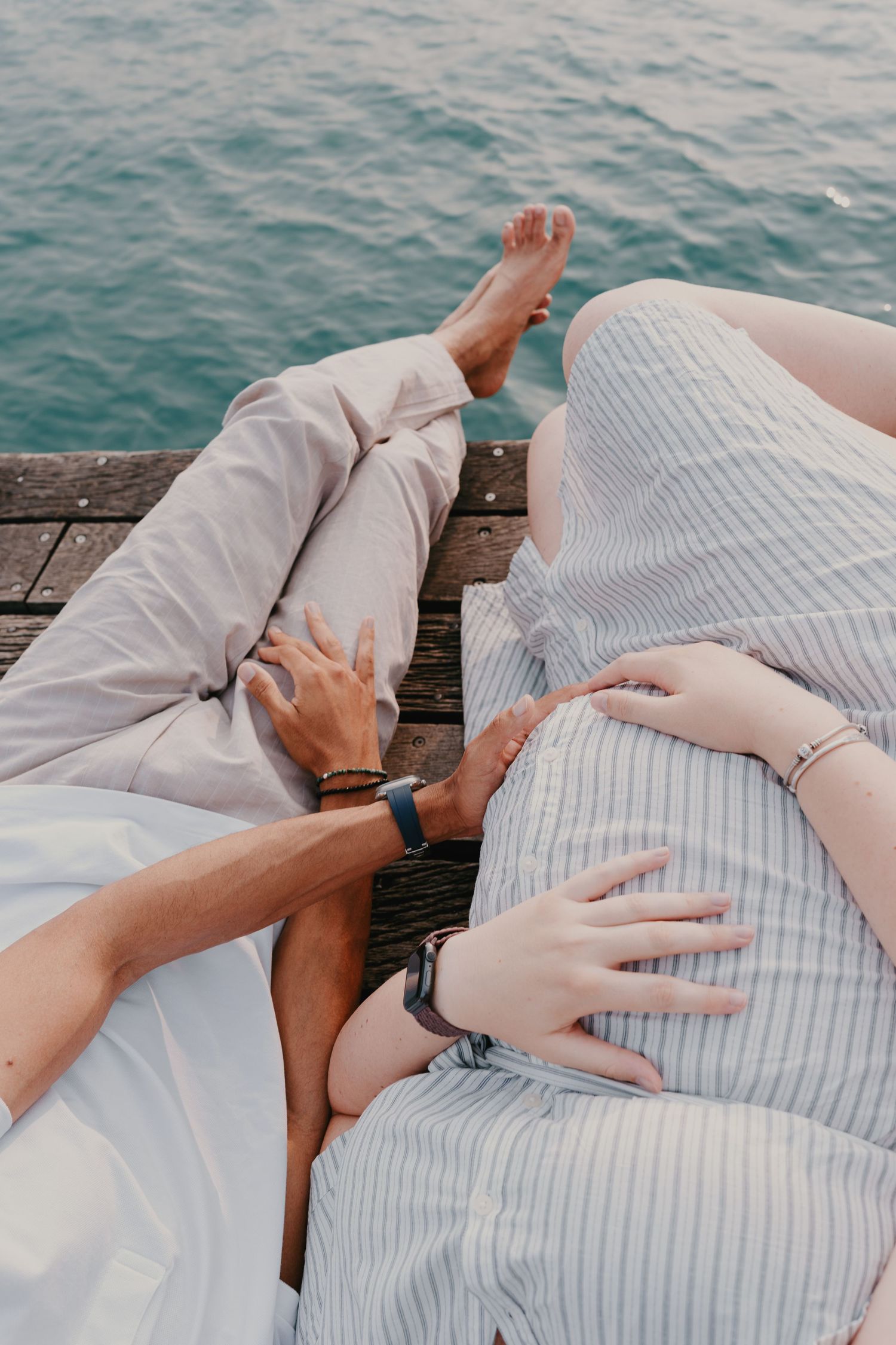 Couple d'amoureux, avec un plan resserré sur le ventre lors d'une séance romantique au bord du lac, photographe mariage et couple.