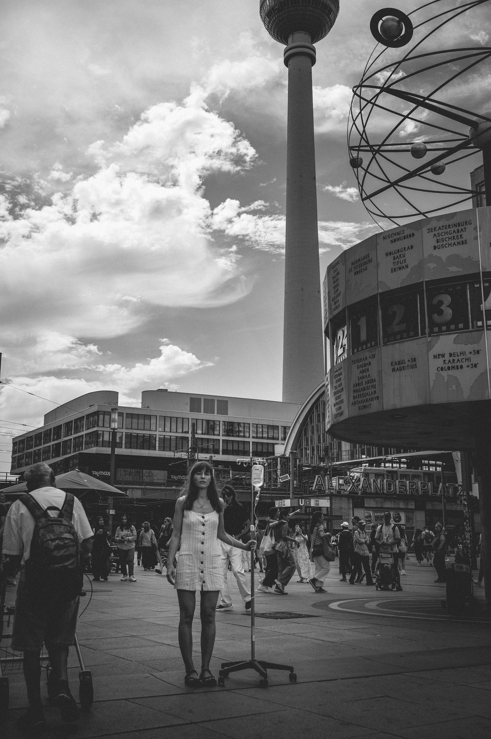 A black and white panoramic series of urban street scenes shows people walking near modernist architecture.