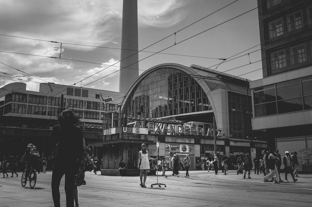 People walk through the interior of a train station during a cloudy day with dramatic lighting.
