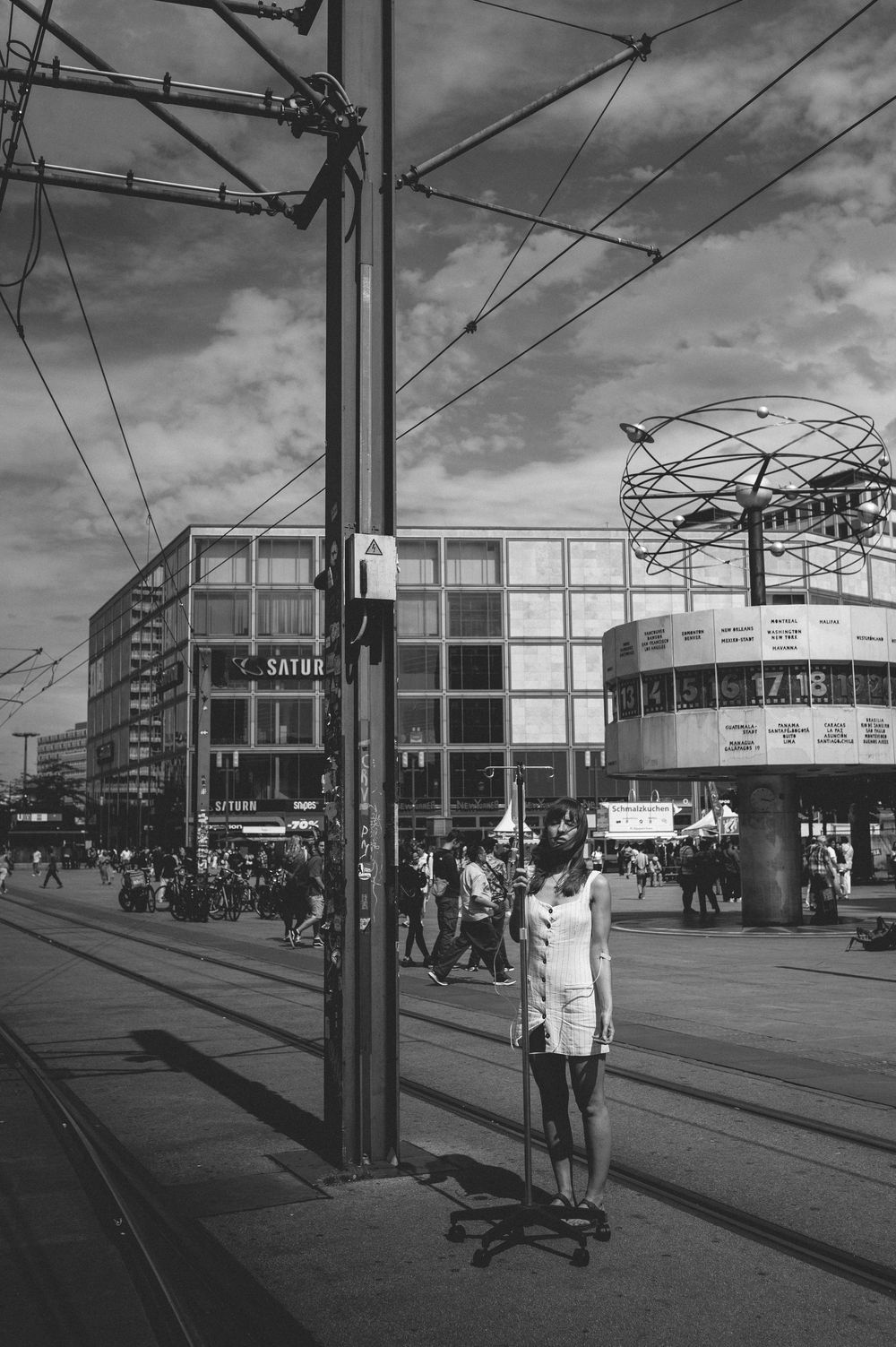 A sequence of black and white street photographs showing people waiting at a tram or bus stop in an urban setting.