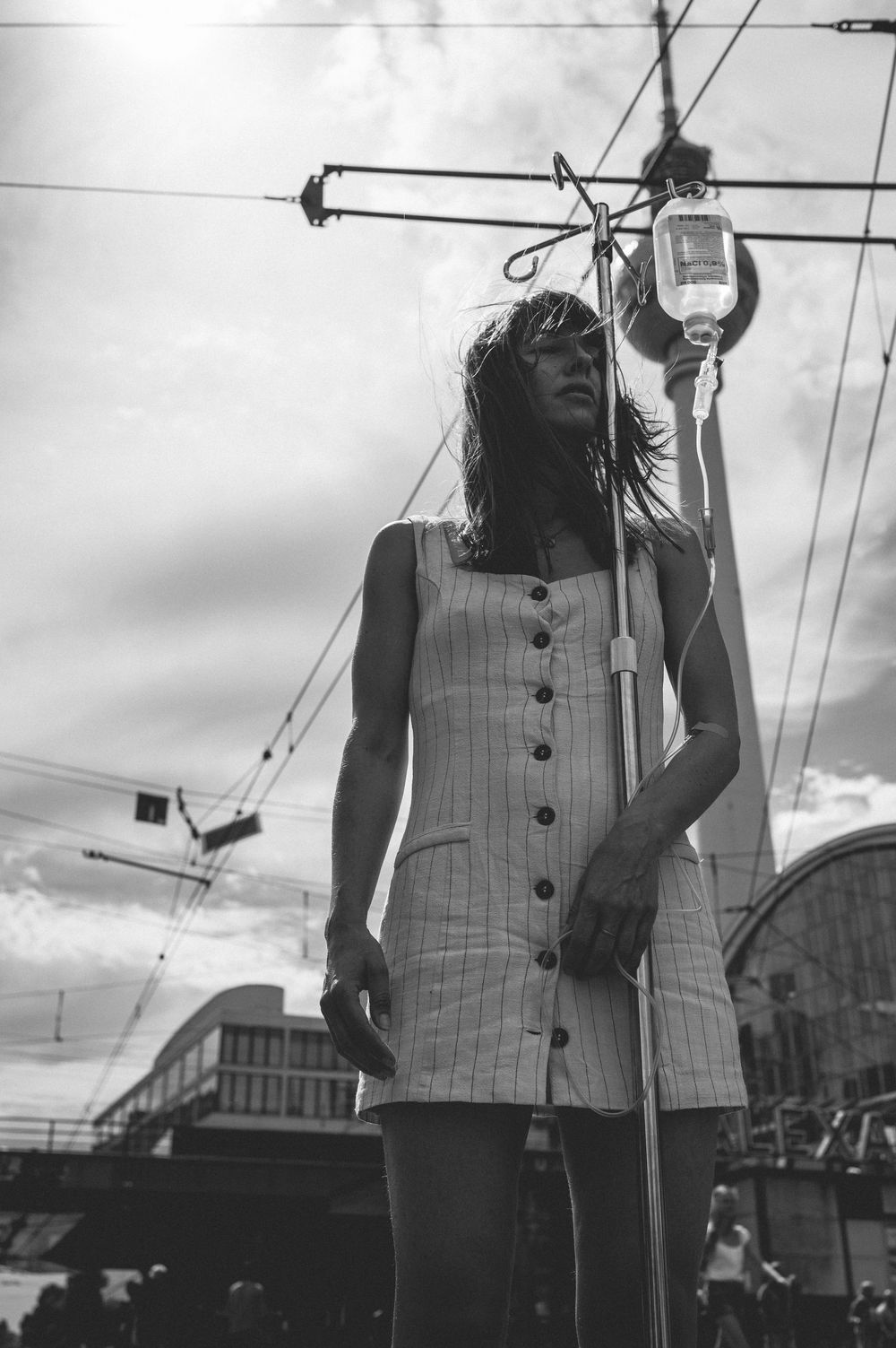 Black and white photo of someone wearing a vintage plaid vest performing outdoors against a cloudy sky.