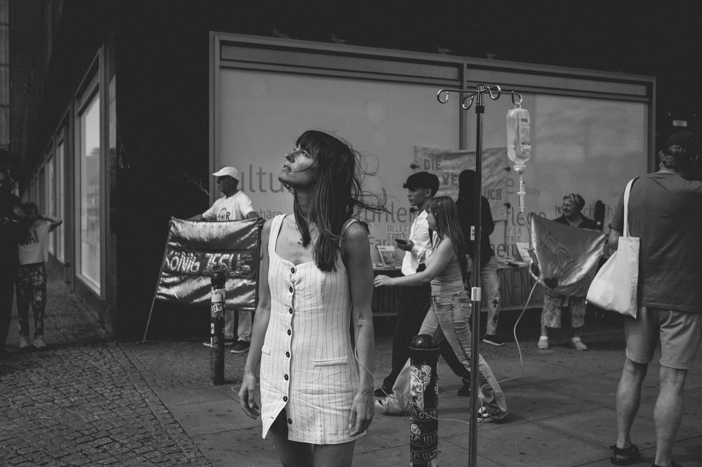 A street scene captured in black and white with vintage styling shows people on a sidewalk in an urban setting.