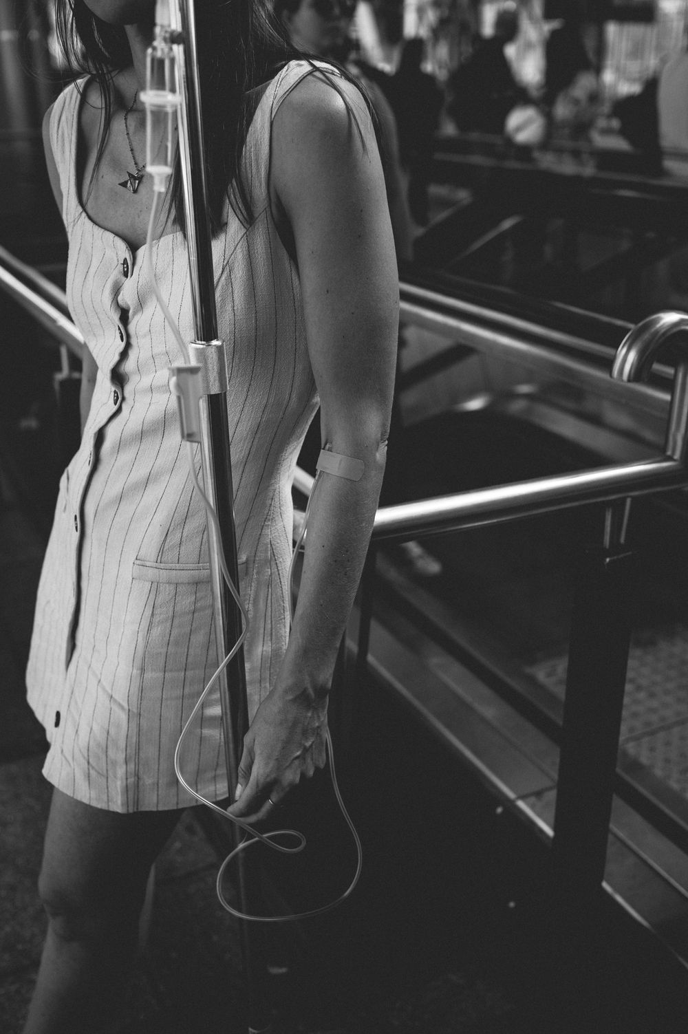 Black and white photo showing an arm with headphone wires against a background of fitness equipment in a gym setting.