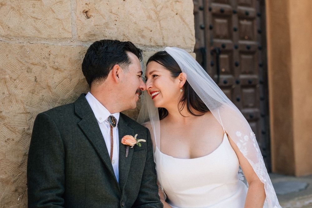 Portrait of couple beneath historic stone archway outside California courthouse