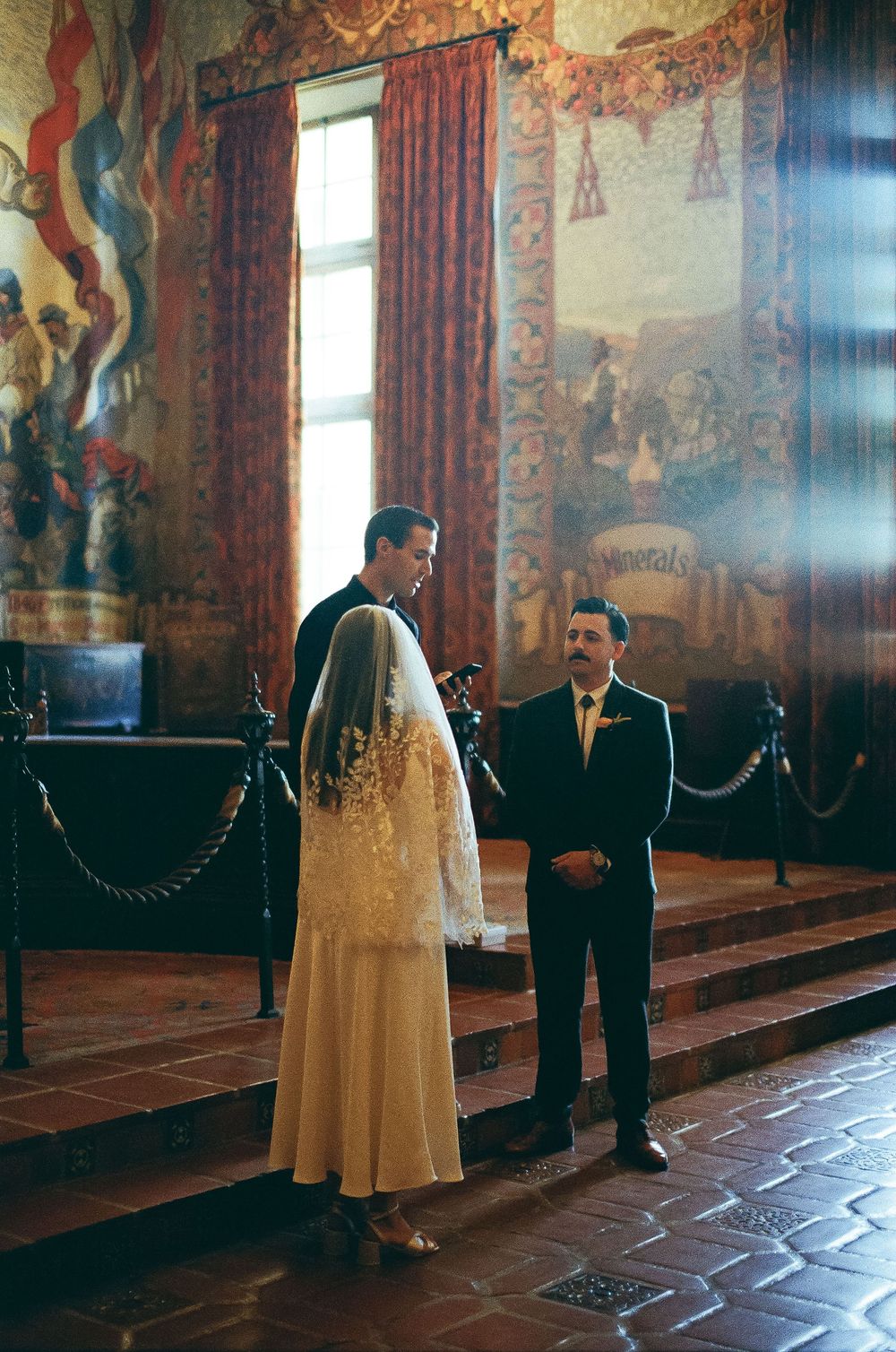 35mm film photo of groom holding vow book outdoors.