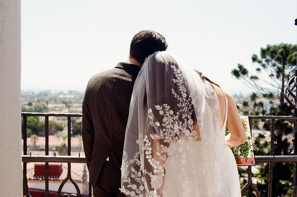 35mm film photo of bride adjusting veil under courthouse archway.