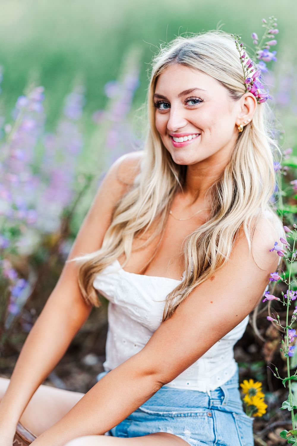 A bright summer portrait in a lavender field with blonde hair and a white top against a soft green background.