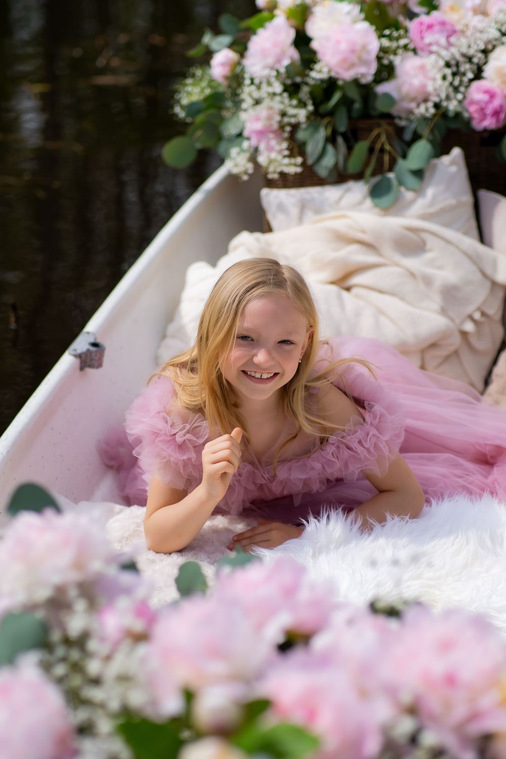 A dreamy portrait session with soft pink florals and white fur styling elements in an elegant garden setting.