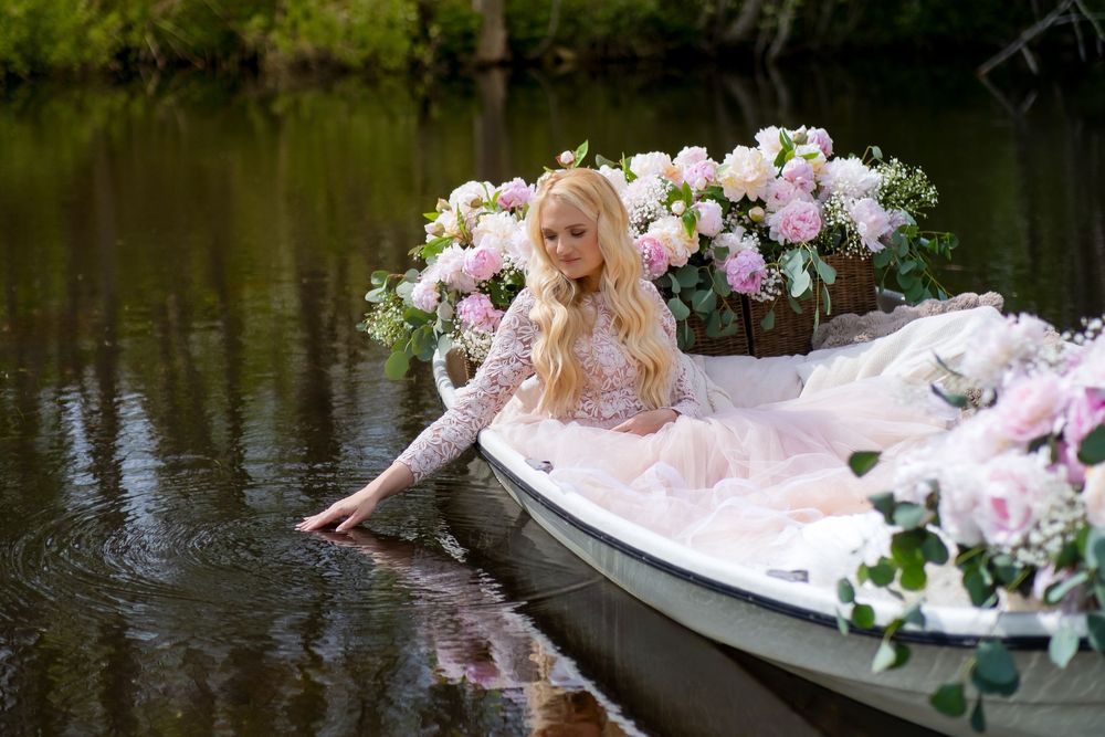 A decorative boat filled with pink and white floral arrangements floats peacefully on a serene lake.