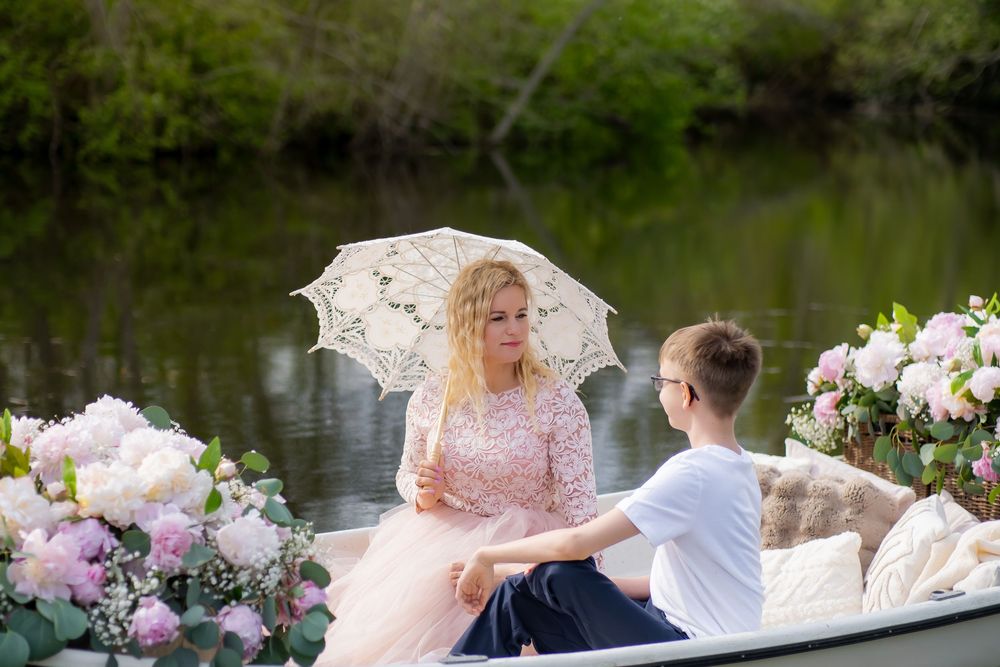 A lush garden wedding reception setup with pink floral arrangements and chairs arranged next to a serene pond.
