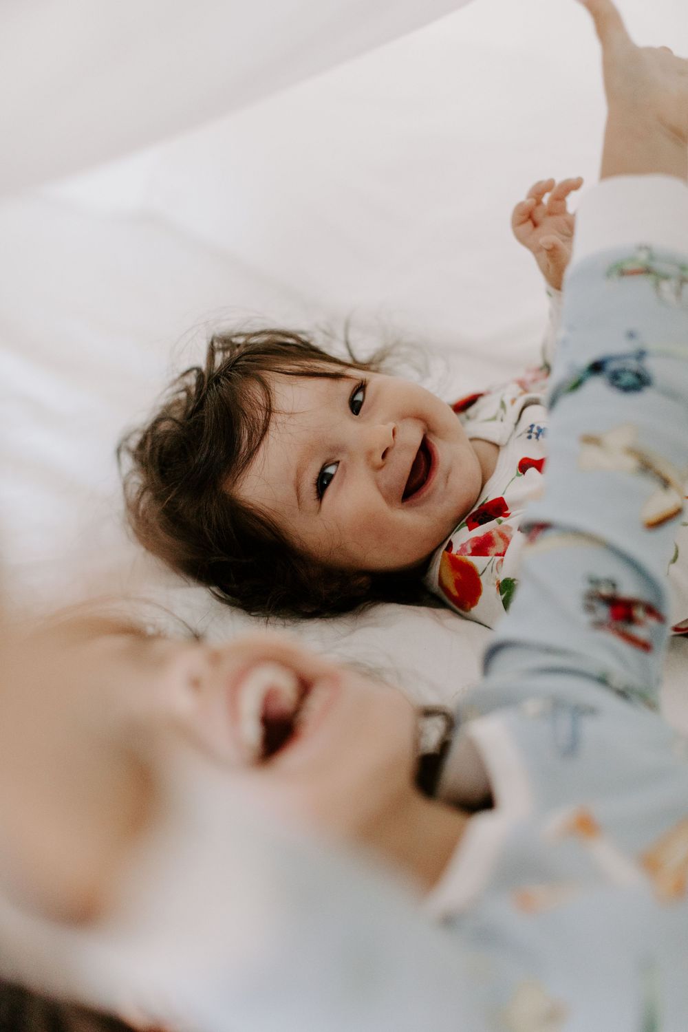 Child lying on white bedding with floral pattern pajamas.