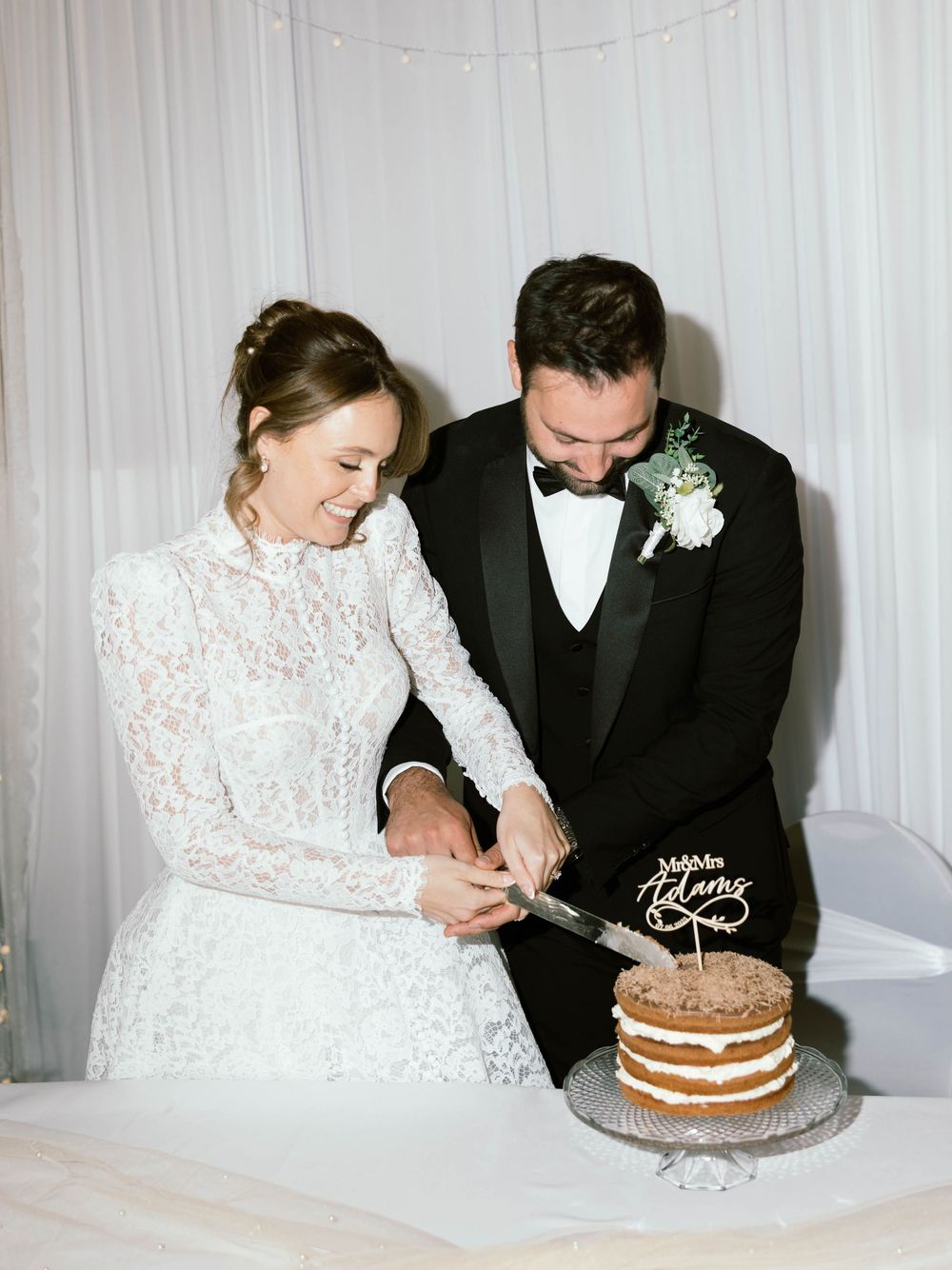 A wedding couple cutting into their rustic naked chocolate layer cake during their reception.