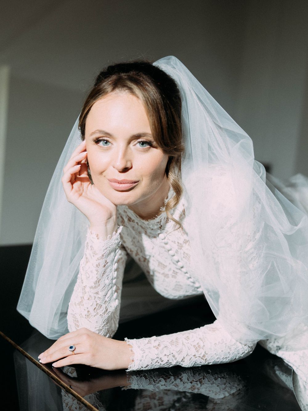 Romantic bridal portrait featuring ethereal lace and tulle veil in a dreamy indoor setting.