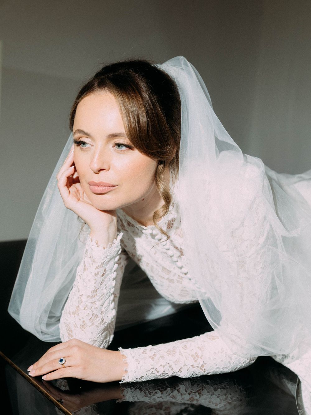 A person wearing a bridal veil poses artistically on a surface in a series of dreamy, artistic shots.