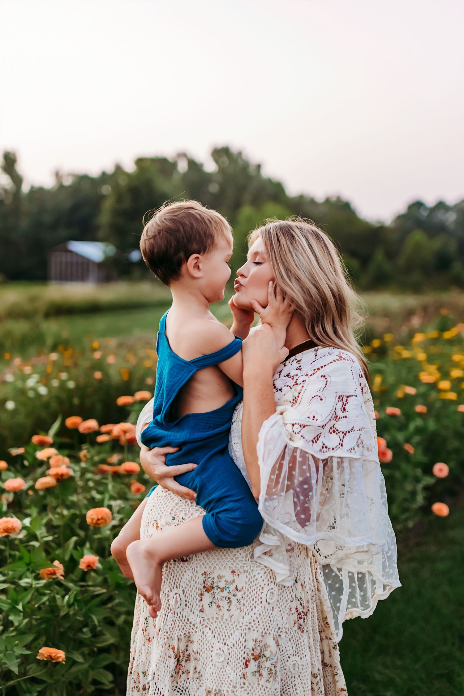 A tender moment between parent and child in a blooming summer flower garden with orange blooms at sunset.