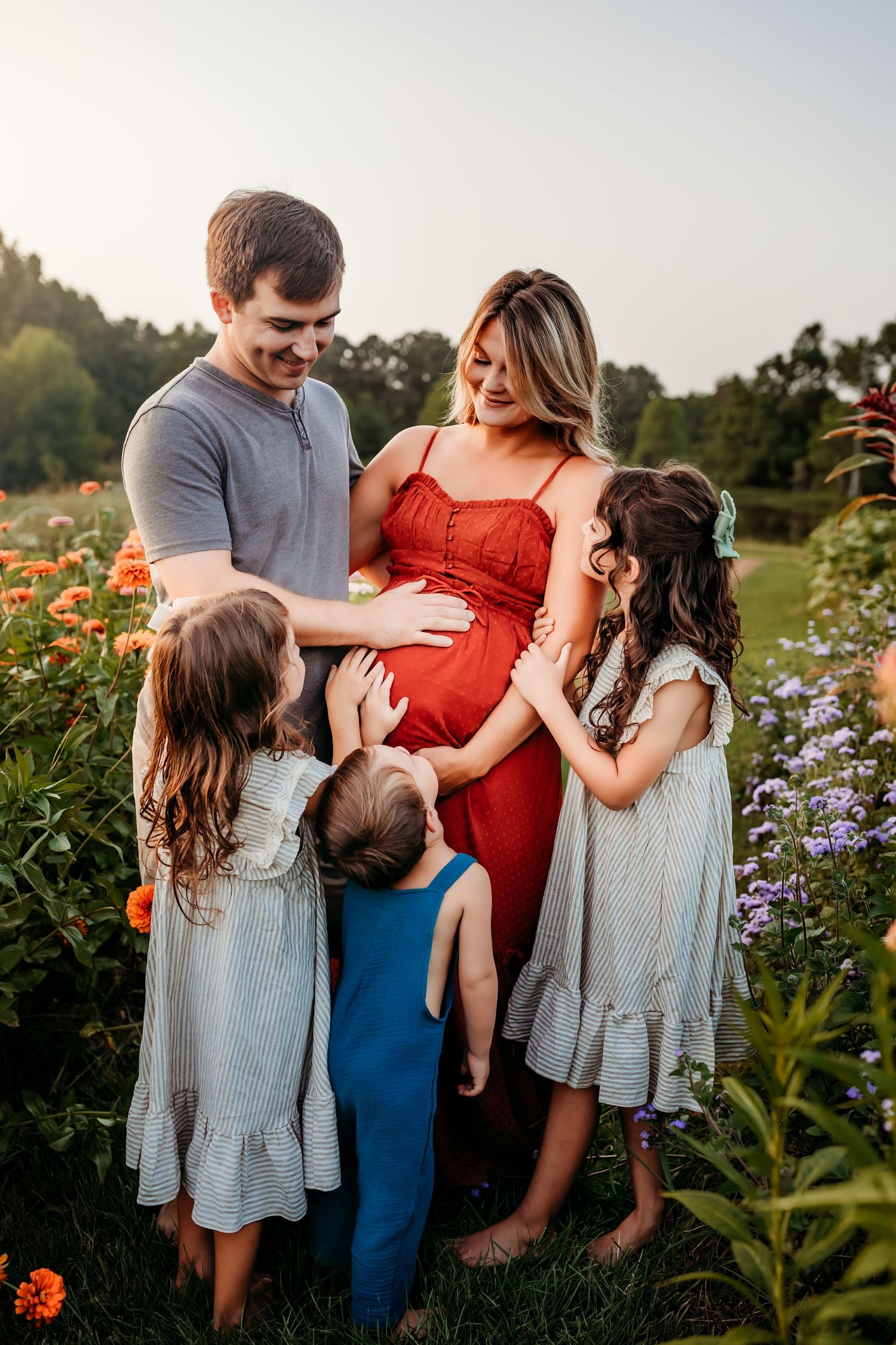 A family shares a tender moment together in a garden with blooming flowers at sunset.